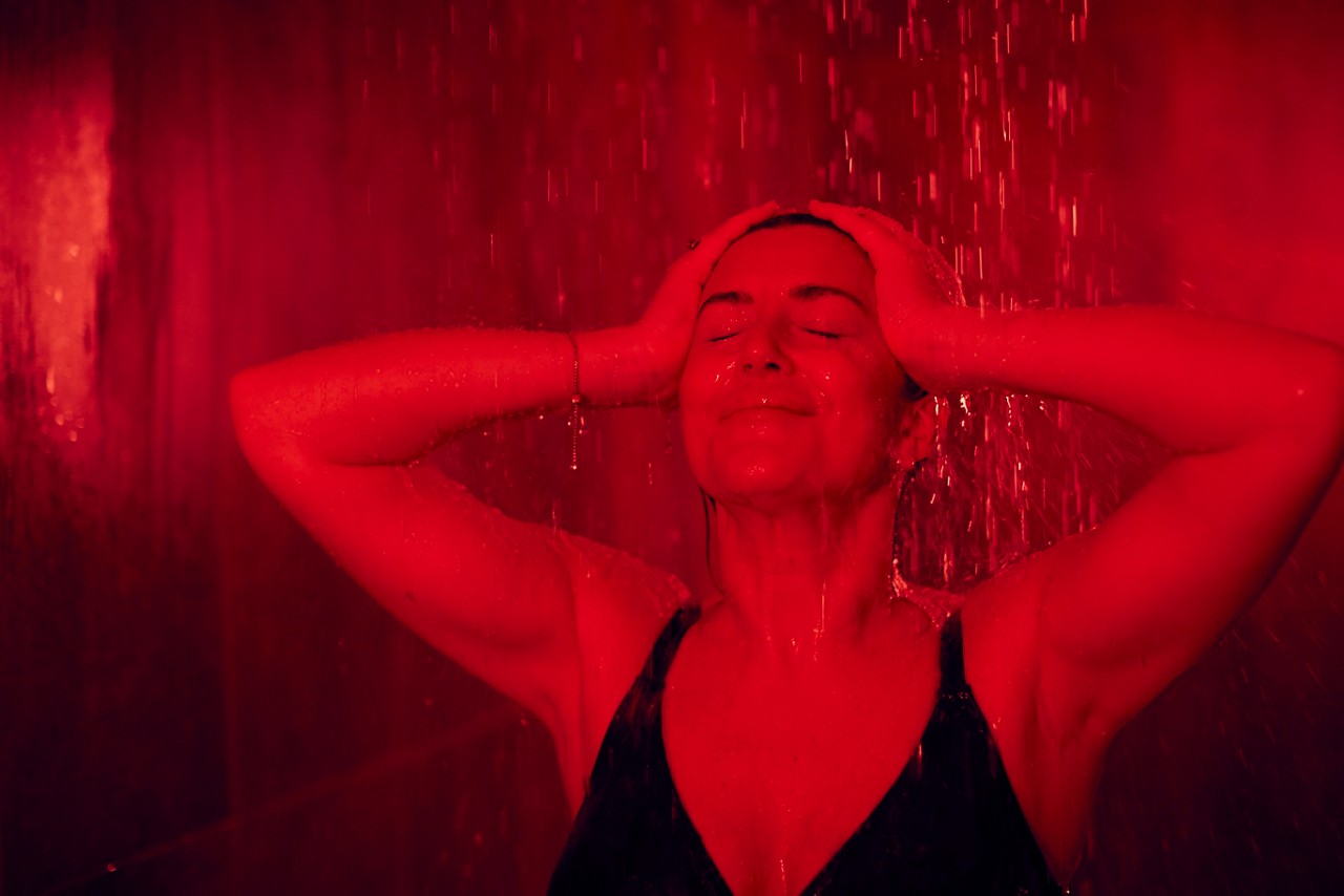 Woman standing under the Rain Walk shower with water flowing over her head.